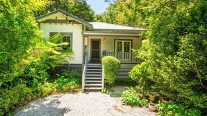 Ein kleines, eingeschossiges Haus mit einer Veranda und einer Treppe zum Eingang.