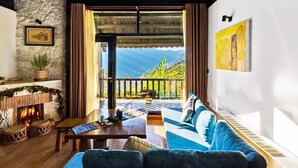 Un salon chaleureux avec une cheminée, un canapé, une table basse et une vue sur l’extérieur.