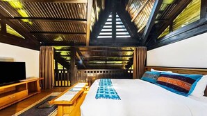 Une chambre avec un grand lit, une télévision et une structure de plafond en bois.