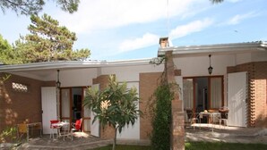 A two-story house with a patio area, a small tree, and outdoor furniture.