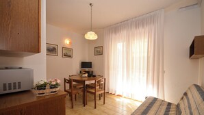 Une pièce chaleureuse avec une table à manger en bois, des chaises, un canapé et un téléviseur.