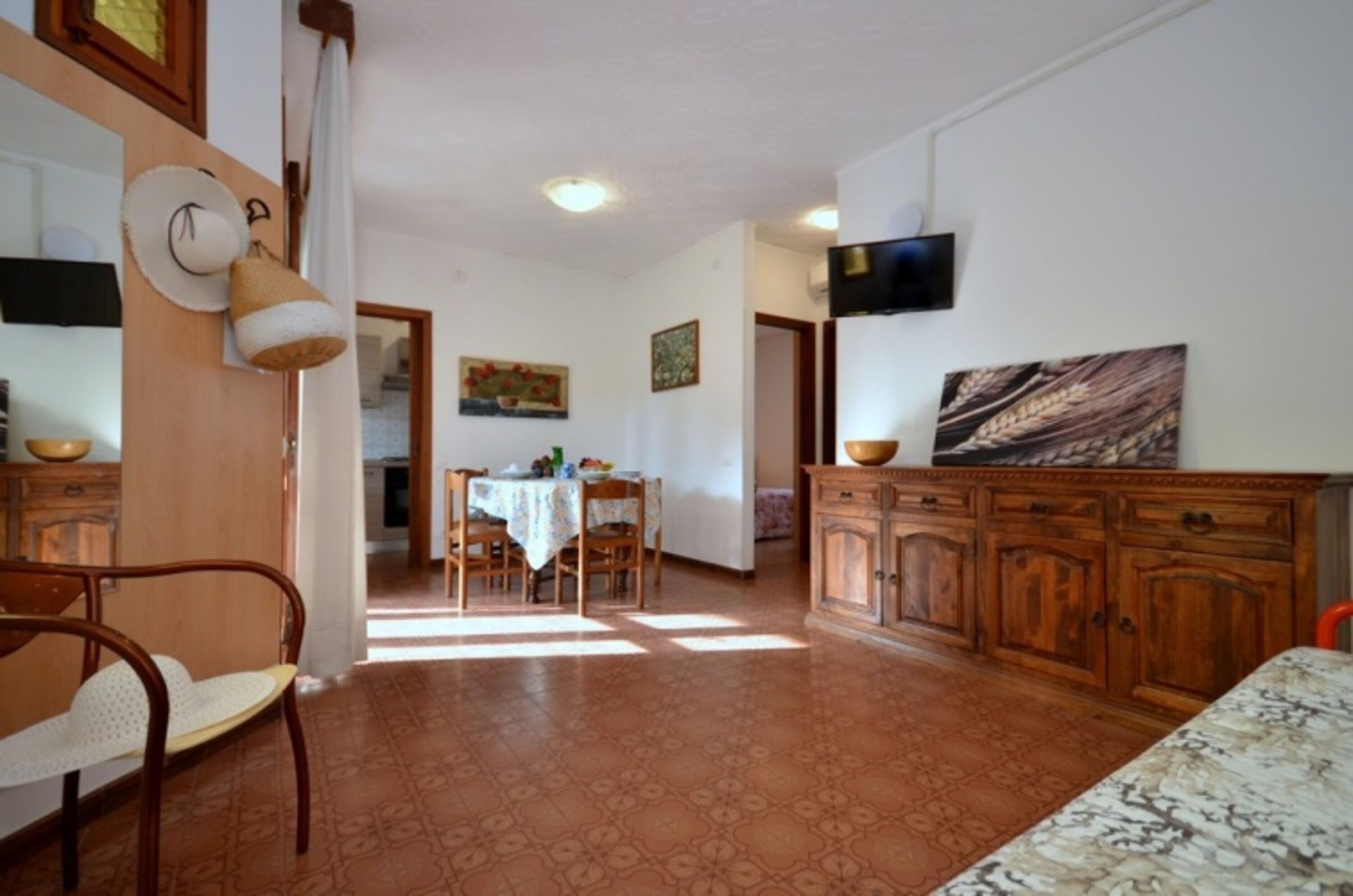 Eine Küche mit Esstisch, Stühlen, einem Fernseher und einem Bild an der Wand.