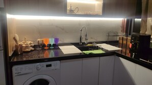 A compact kitchen with a built-in washer, a sink, and a microwave. - Large and beautiful app, large stad ibnoubatouta 15mm Tangier Airport (Tanger)