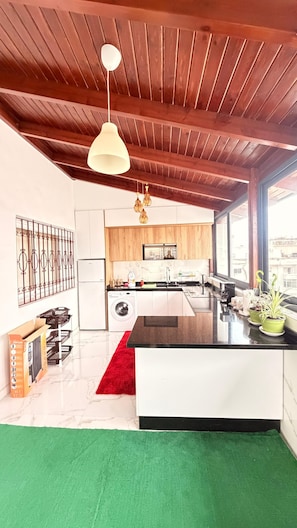 Una cocina moderna con una isla central, vigas de techo de madera y un gran ventanal con vistas a la ciudad.