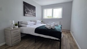 A bedroom with a bed, a nightstand, a window, and a cityscape painting. - 4 Bed Apartment in Warwick (Warwick)