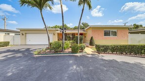 A single-story house with a garage, palm trees, and a well-maintained front yard.