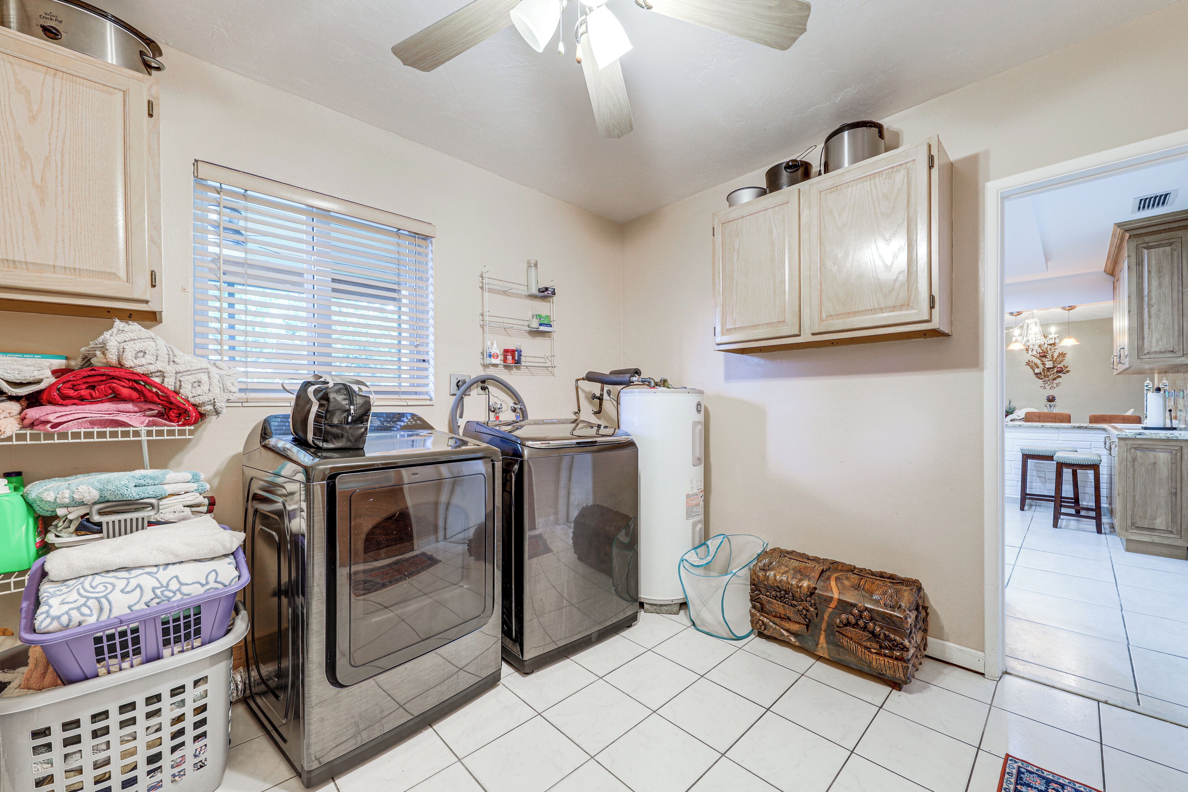 A compact kitchen with built-in appliances, a window with blinds, and a view into a dining area.