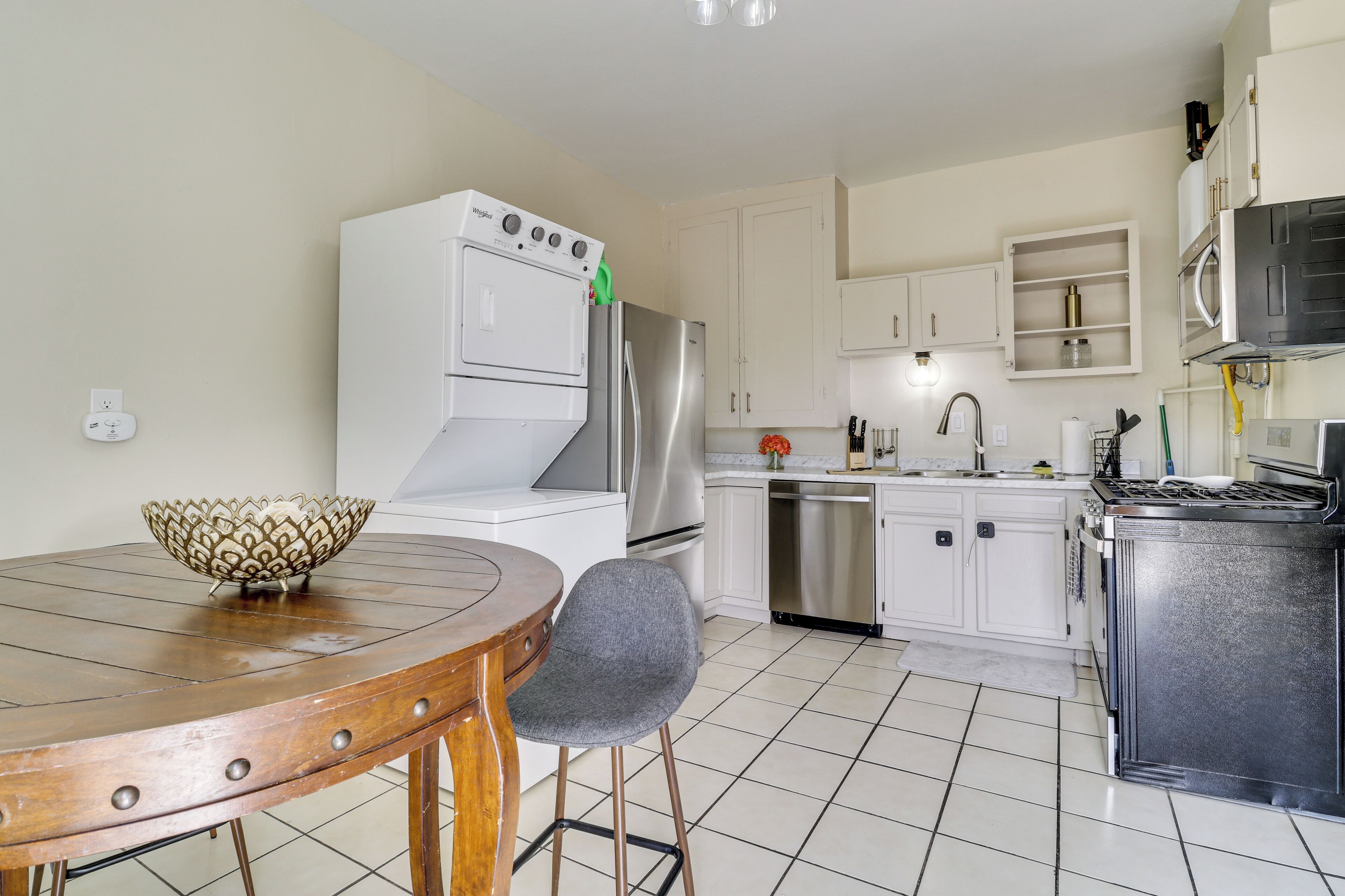 A kitchen with white cabinets, a stainless steel refrigerator, a built-in oven, and a microwave.