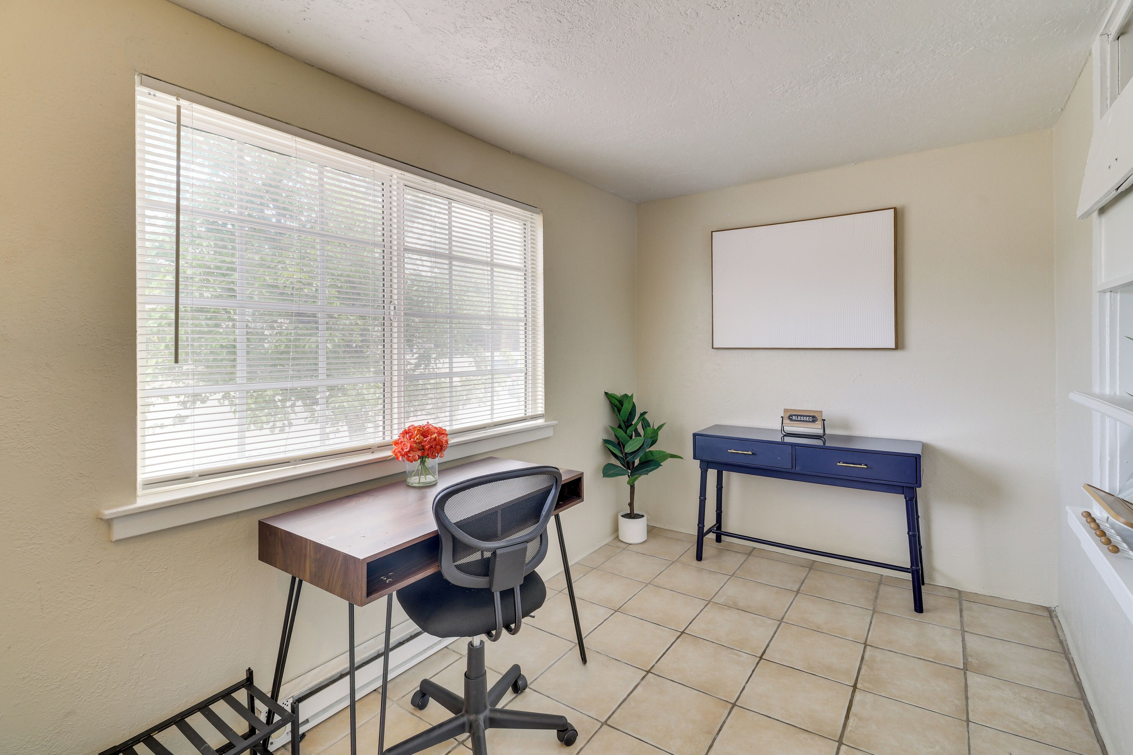 A small office space with a desk, chair, and a potted plant.