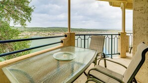 Ein Balkon mit Glastisch und Stühlen, mit Blick auf Wasser und Grünflächen.