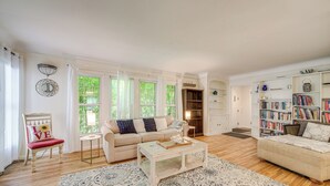 A spacious living room with a beige sofa, a coffee table, and a bookshelf filled with books. - 9 Mi to Cleveland: Home Near Hospitals & Colleges (University Heights)