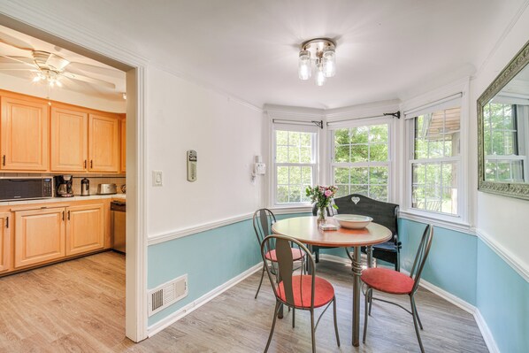 A kitchen with wooden cabinets, a dining table with chairs, and a ceiling fan.