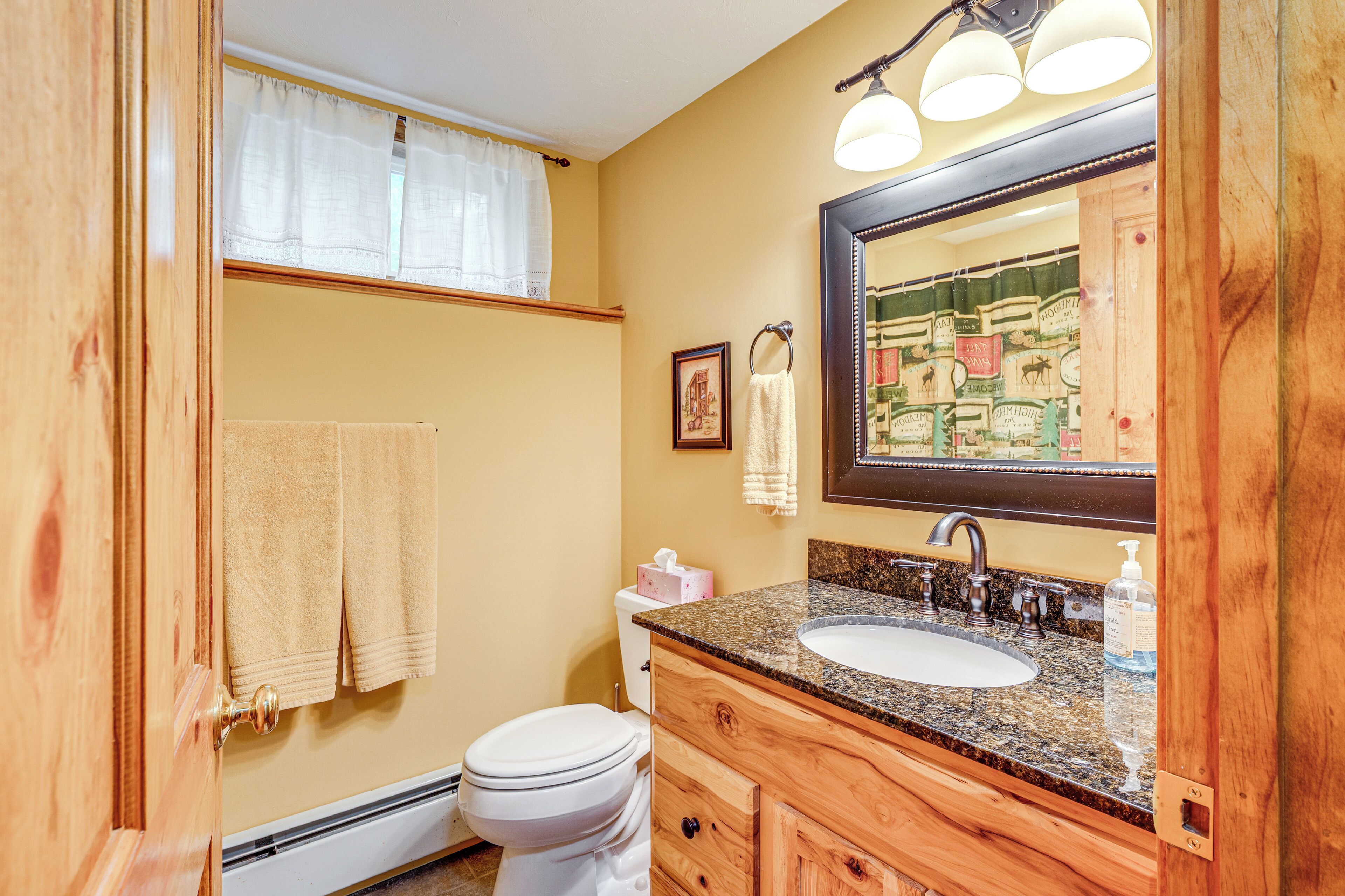 Un baño con tocador de madera, lavabo blanco y un espejo grande.