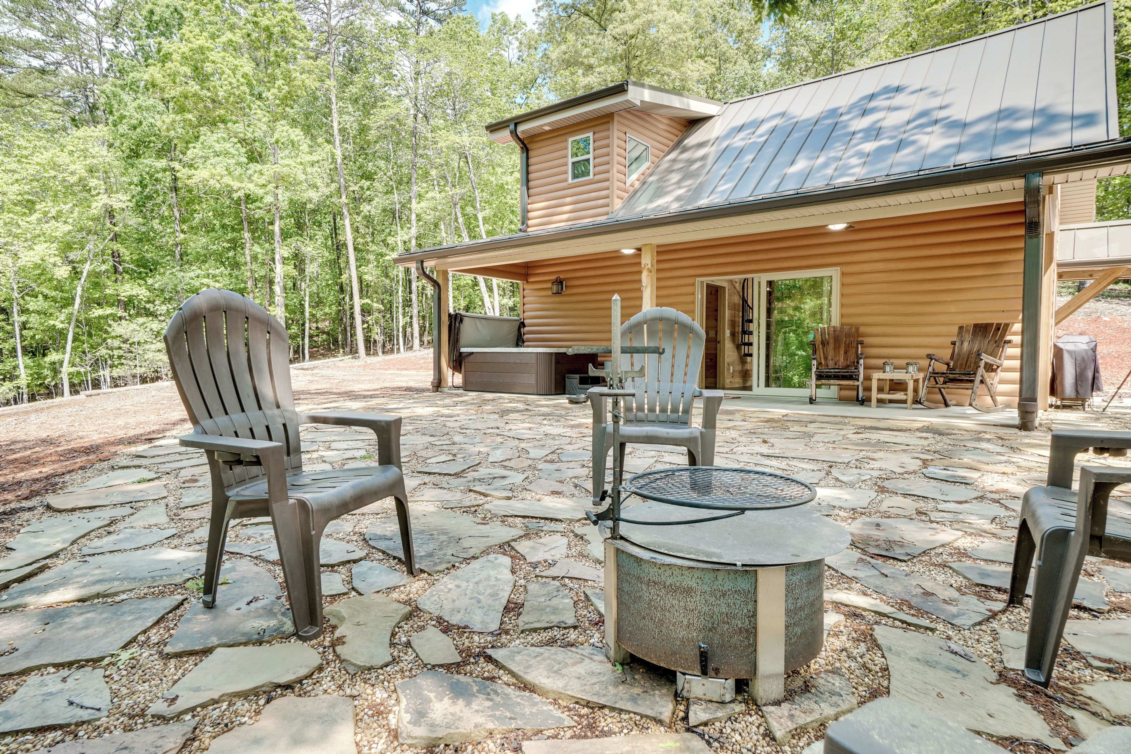 A cabin with a stone patio, outdoor seating, and a fire pit.