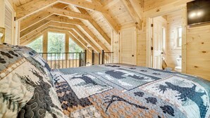 A wooden cabin with a high ceiling, a large bed with a patterned quilt, and a view of the outdoors through a window. - Sip, Hike & Explore: Sleek Retreat in Cleveland! (Cleveland)