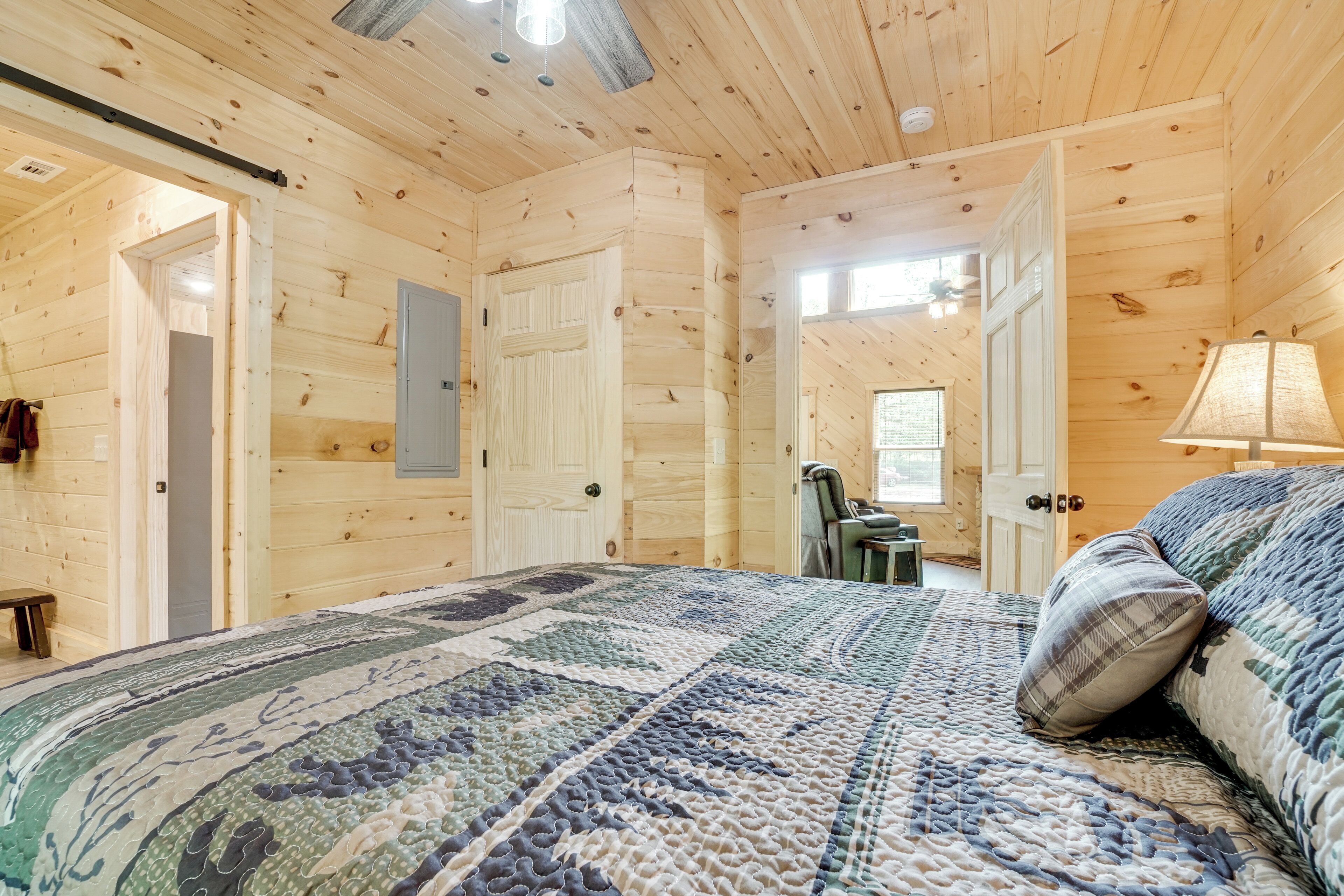 Ein Holzhüttenraum mit einem Bett, einem Schreibtisch und einem Stuhl.
