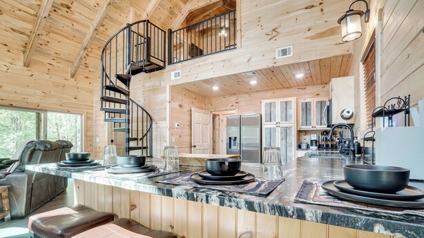 A wooden cabin interior with a kitchen, dining area, and a spiral staircase. - Sip, Hike & Explore: Sleek Retreat in Cleveland! (Cleveland)