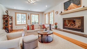 A spacious living room with a fireplace, large windows, and a cozy seating area.
