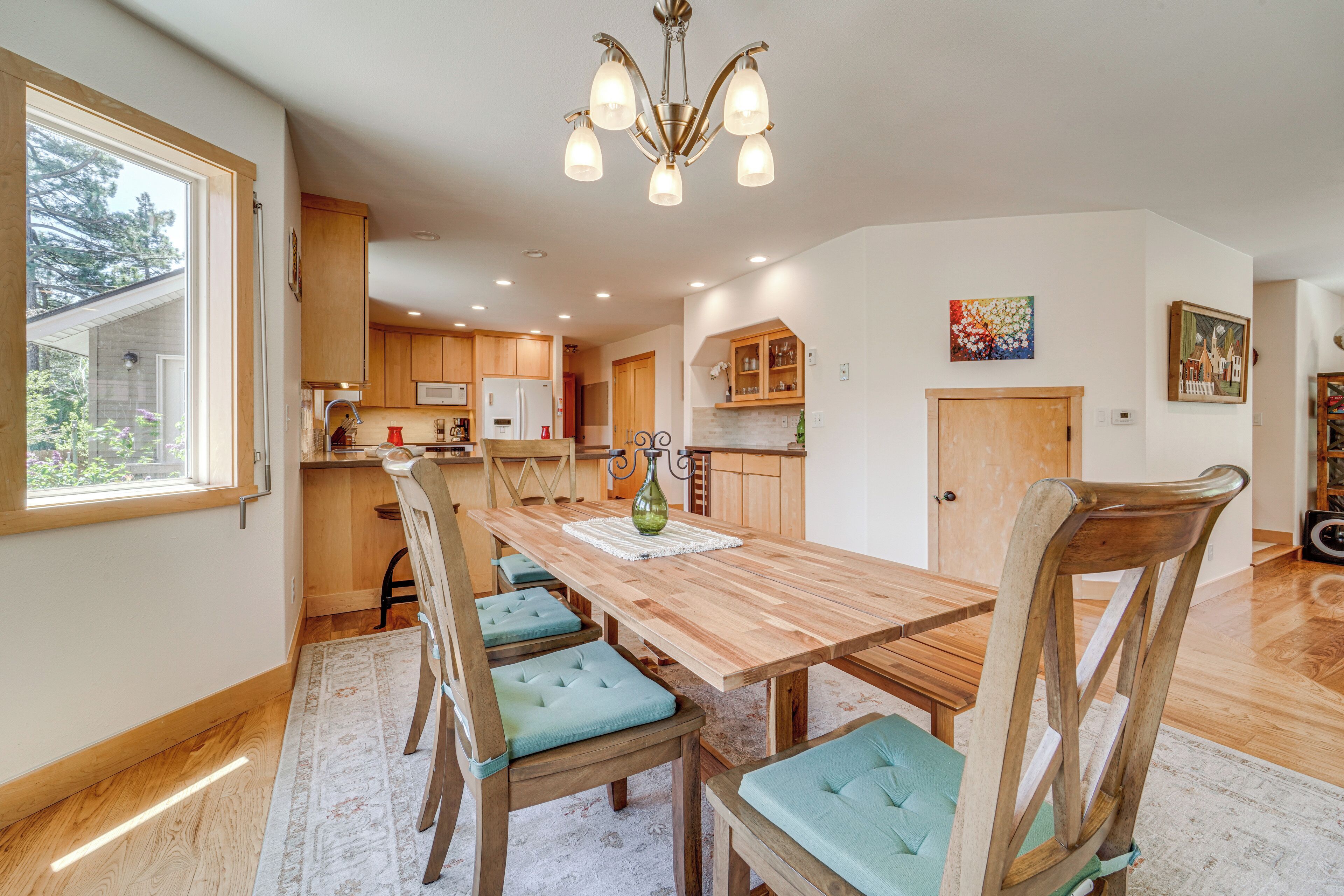 A spacious kitchen with wooden cabinets, a large dining table with chairs, and a chandelier.