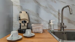 Una cocina moderna con protector de encimera de mármol, un lavamanos de acero inoxidable, una cafetera y una cesta de mimbre.