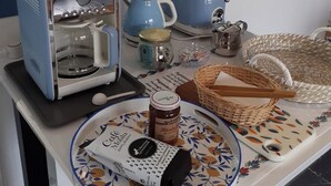 Una encimera de cocina con cafetera, tostadora y un plato con un tarro de mermelada.