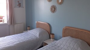 Un dormitorio con dos camas, una ventana con cortinas y adornos en la pared.