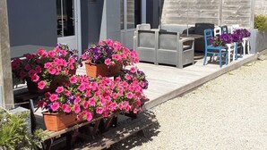 Un patio con mobiliario exterior, un paraguas a rayas y macetas con flores.