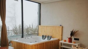 A modern bathroom with a wooden bathtub, a large window, and a view of trees outside. - Ordu Bungalov Loın Du Monde (Persembe)