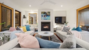 Ein modernes Wohnzimmer mit Kamin, Sofas und Fernseher.