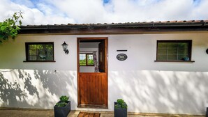 A white building with a wooden door, two windows, and a small sign. - Bluebells by STAE-Homes (Bristol)