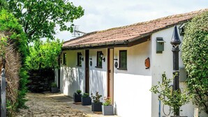 A building with a cobblestone path leading to a white facade with a tiled roof. There are potted plants along the path and a small garden area to the right. - Lavender by STAE-Homes (Bristol)