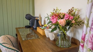 A wooden table with a coffee maker, a box of snacks, and a vase of flowers. - Rose by STAE-Homes Su (Bristol)