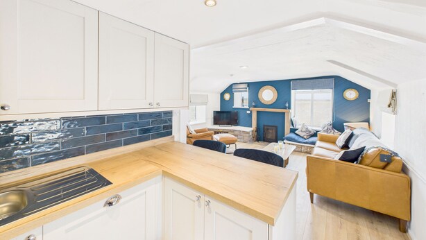 A modern kitchen with a wooden countertop and white cabinets. - Host & Stay | St Cuthbert's Cottage (Seahouses)
