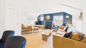 A spacious living room with a fireplace, a sofa set, and a television. - Host & Stay | St Cuthbert's Cottage (Seahouses)