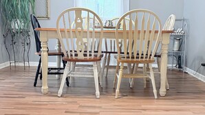 Un'area pranzo con un tavolo e sedie in legno, una pianta in vaso e una finestra con tende.