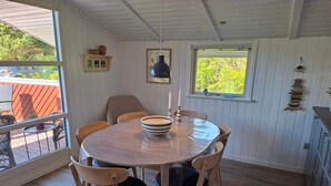Un comedor con una mesa redonda, seis sillas y un ventanal con vistas a la vegetación.