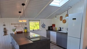 Una cocina moderna con una isla central, muebles blancos y un tragaluz.