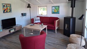 Una sala de estar acogedora con un sofá rojo, un televisor, una mesita y una chimenea.