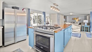 A modern kitchen with a central island, stainless steel appliances, and a view to the living area. - Unique West Harwich Vacation Compound w/ Pool RPAM111 (West Harwich)