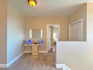 A hallway with a marble floor, a mirror above a vanity, and a door leading to a bedroom.