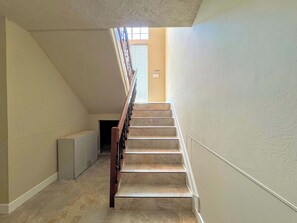 A staircase with a handrail, leading to a landing with a window.