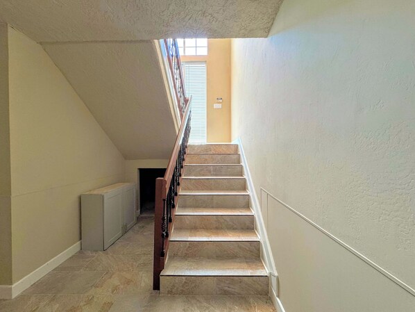 Una escalera con barandilla que lleva a un rellano con ventana.