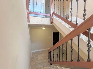 Una escalera con barandilla de madera y balaustradas de metal decorativo que conduce a un piso superior.