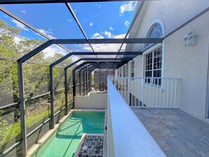 A covered outdoor area with a pool, glass walls, and a white railing.
