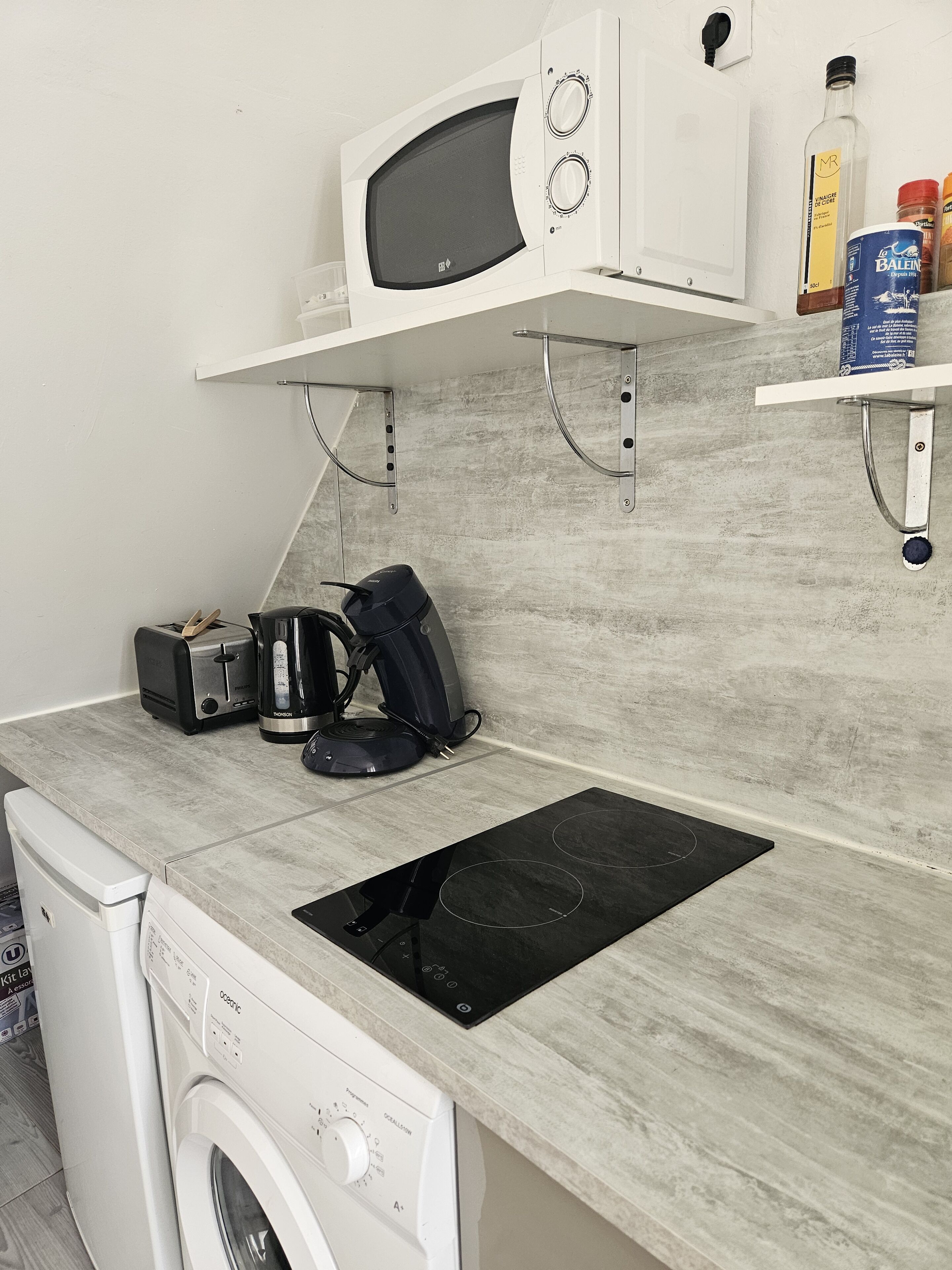 Una cocina compacta equipada con microondas, tostadora, cafetera y cocina integrada.