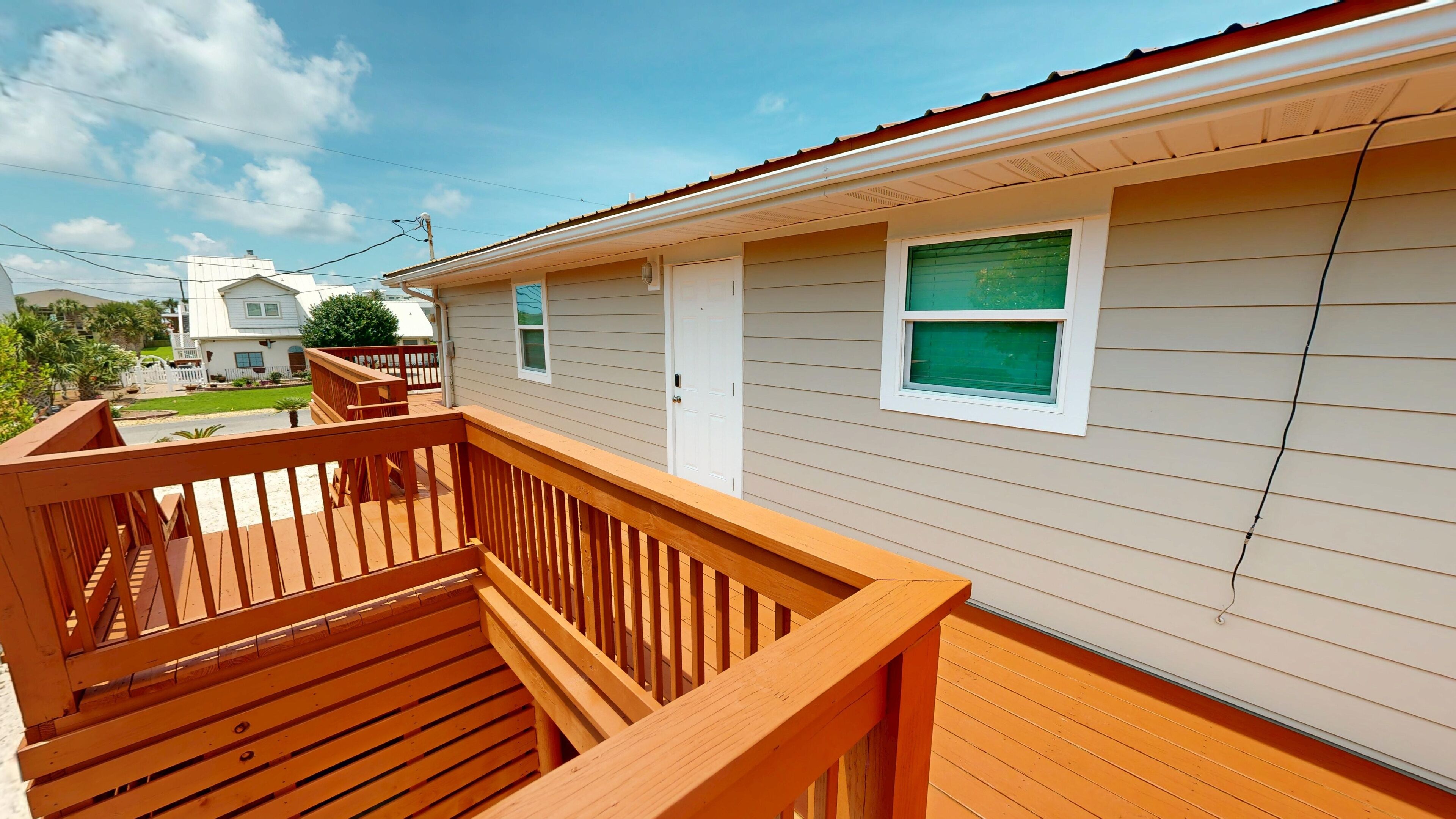 A residential building with a wooden deck, a garage, and a white door.