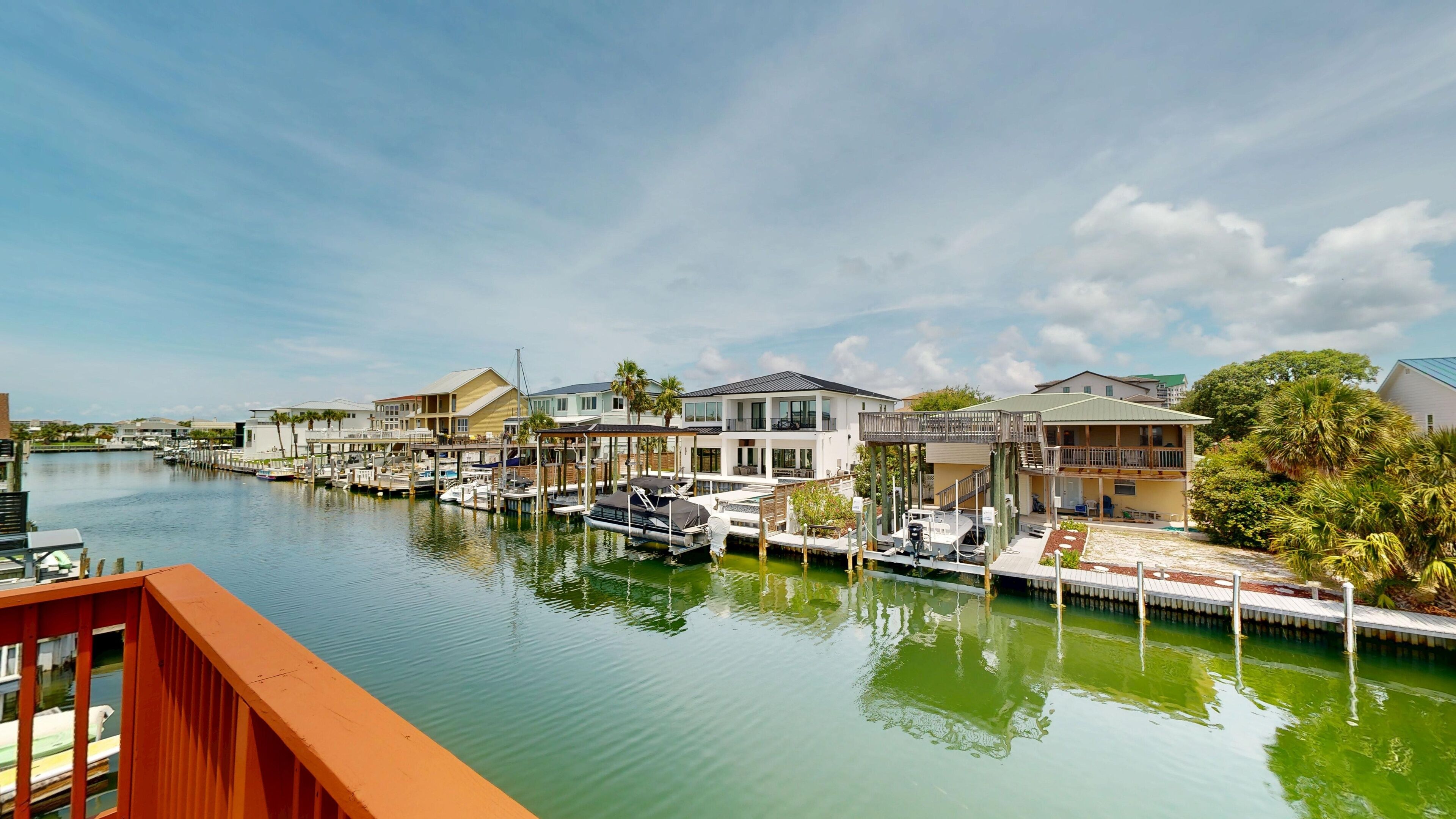 Un port de plaisance avec des bateaux amarrés, des maisons au bord de l’eau et un ciel dégagé.