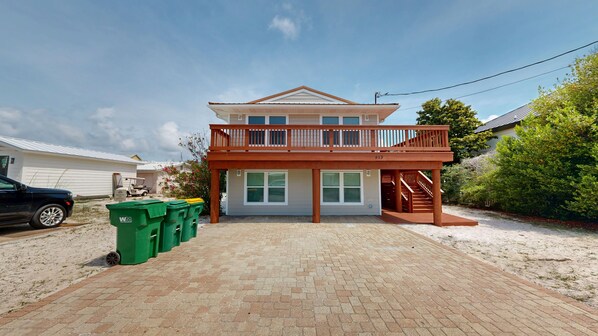 A two-story house with a balcony and a covered porch. - Canal Breeze Cottage 4 Bedroom Home (Destin)
