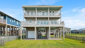 A multi-story building with a covered front porch, a second-floor balcony, and a garage. - B3 Sand Ranch 4 Bedroom Home (Port Bolivar)