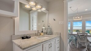 A bathroom with a large mirror, two sinks, and a vanity with drawers. There is a hanging light fixture above the mirror and a lantern on the vanity. - B3 Sand Ranch 4 Bedroom Home (Port Bolivar)